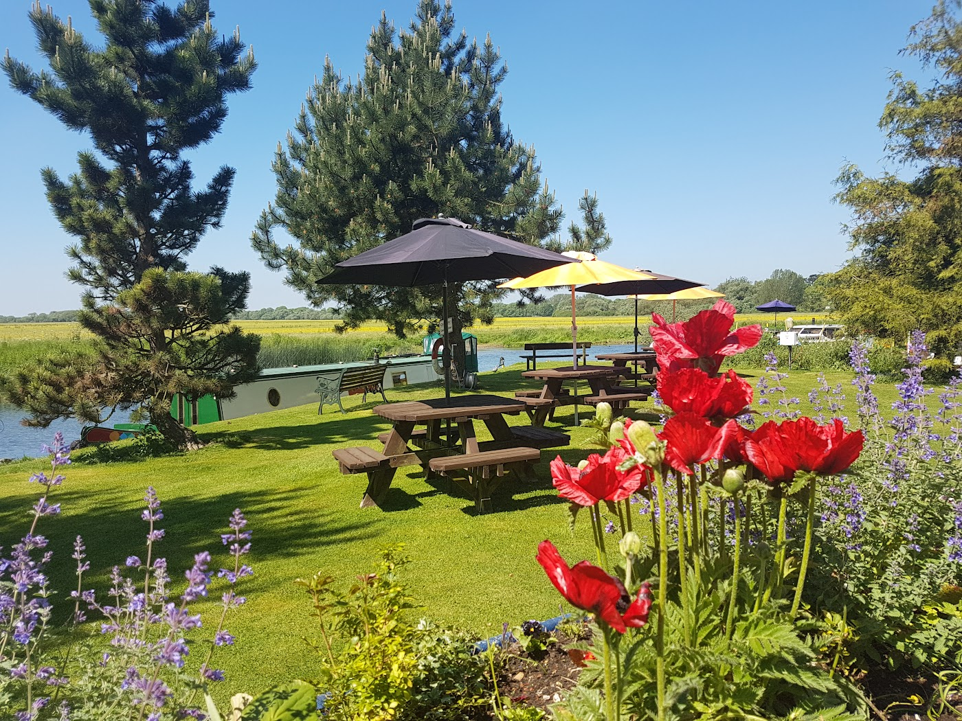 Riverside seating area with picnic tables, umbrellas and beautiful flowers